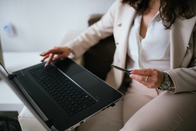 Une personne règle un achat en ligne sur un ordinateur portable, une carte bancaire à la main