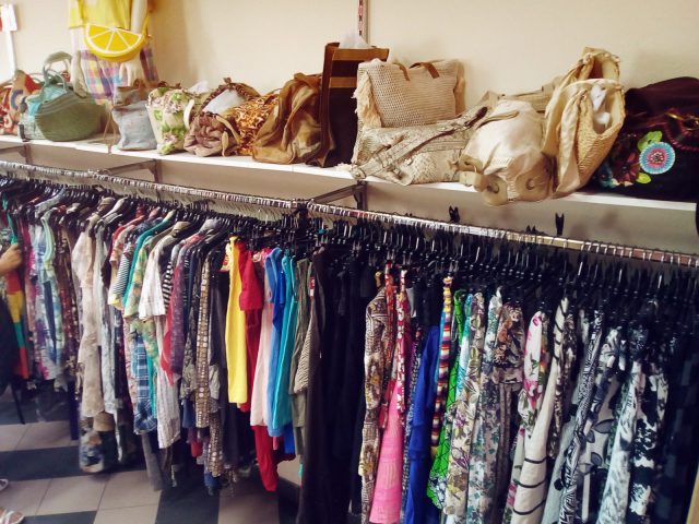 Portants de vêtements d’occasion et sacs exposés dans une boutique de seconde main