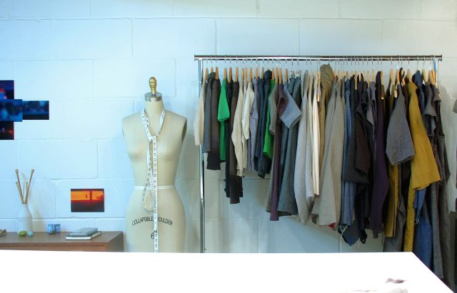 Un portant de vêtements sur cintres à côté d’un mannequin de couture dans un atelier