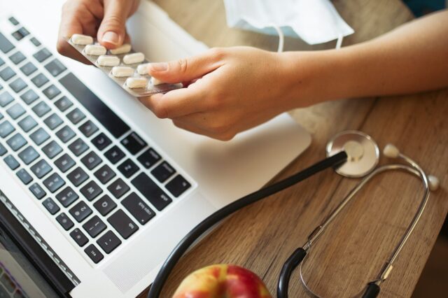Un professionnel de santé organise des médicaments à son bureau, à côté d'un stéthoscope